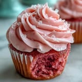 Vibrant pink cupcakes topped with fluffy vanilla buttercream, ready to serve at a cozy afternoon tea party.  