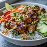 Colorful Rice Paper Roll Bowl featuring grilled tofu, fresh herbs, and a rich, glossy peanut drizzle.
