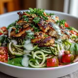 Two servings of Spiralized Vegetable Bowl with spiralized veggies, cherry tomatoes, and sesame seeds on a rustic kitchen counter.