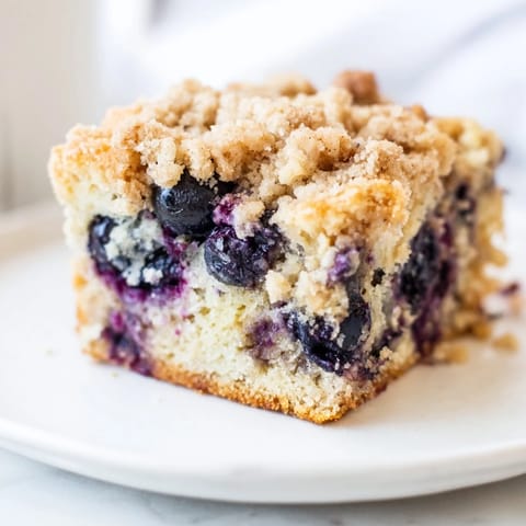 A freshly baked Blueberry Buckle showing a tender, moist cake with a crunchy streusel topping.
