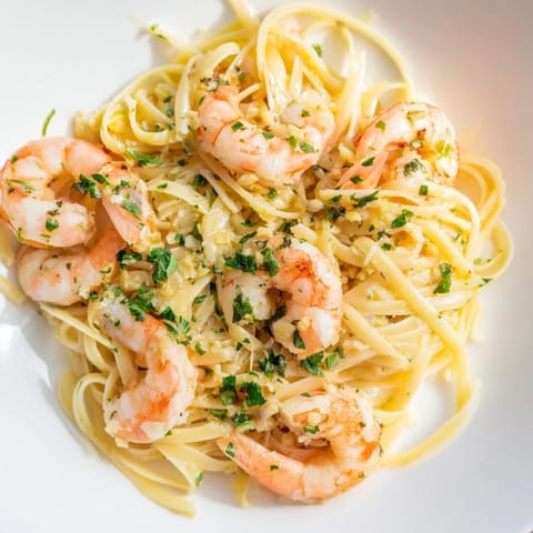 A close-up of garlic butter shrimp linguine topped with Parmesan and a lemon wedge.