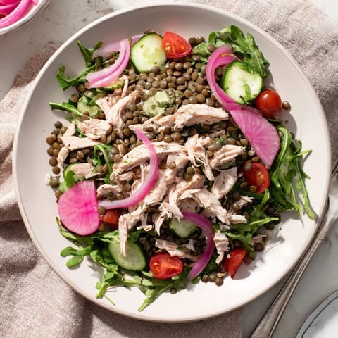 Overhead view of Lentil & Chicken Spring Salad, featuring vibrant cherry tomatoes, pickled onions, and cucumber slices arranged artfully for a fresh lunch.