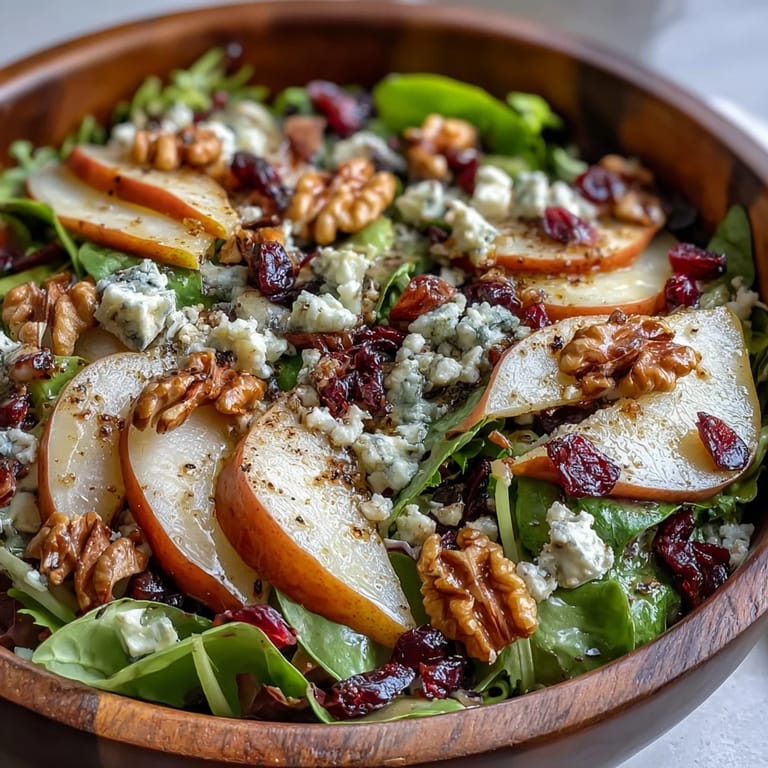 Pear Gorgonzola Salad served on a rustic wooden table, mixing crisp arugula and spinach with sweet pear slices, tangy Gorgonzola, and crunchy walnuts for a refreshing light meal.