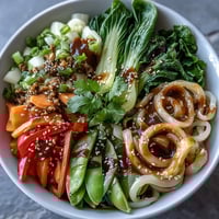 A vibrant shirataki noodle bowl with crisp bok choy, red bell pepper, and snow peas in a fragrant ginger sauce.